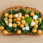 Chickpea and kale toast with feta on wooden background