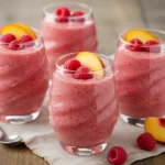 Raspberry peach chia smoothie in swirl glasses with fruit garnish