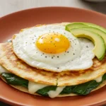 Cheesy egg quesadilla with spinach and avocado on ceramic plate