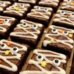 Halloween mummy brownies drizzled with white icing and candy eyes.