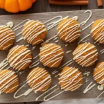 No-Bake Pumpkin Cheesecake Balls arranged on a plate with white chocolate drizzle and cozy fall decor.